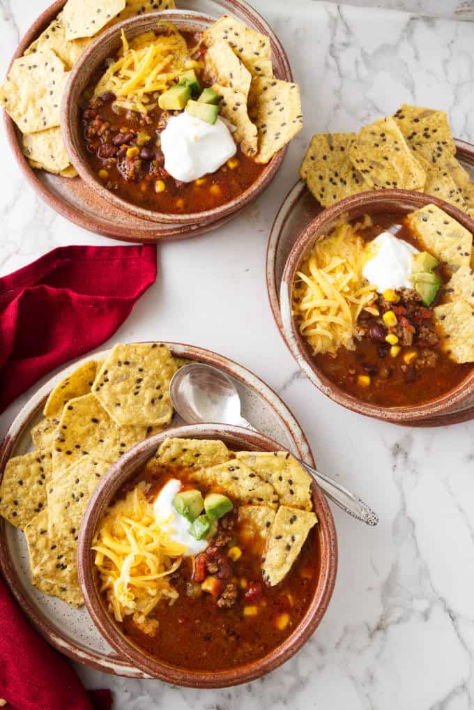 Three bowls of instant pot taco soup with tortilla chips.