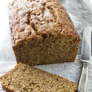 A slice of whole wheat banana bread next to a knife.