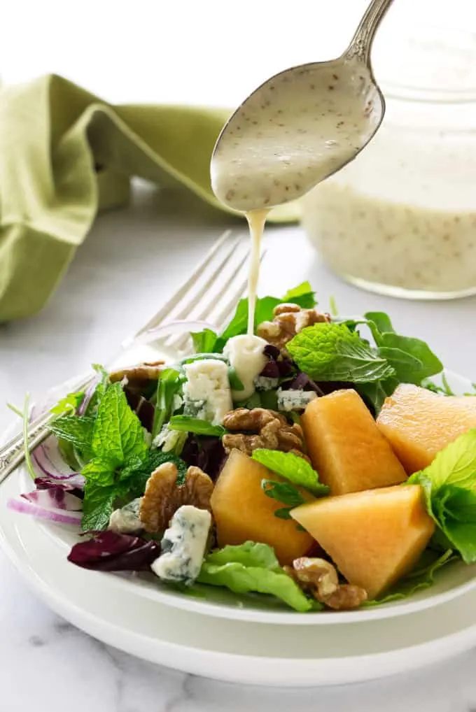 Salad with creamy orange champagne dressing being spooned on