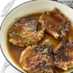 Four pork chops in a skillet with honey garlic glaze.