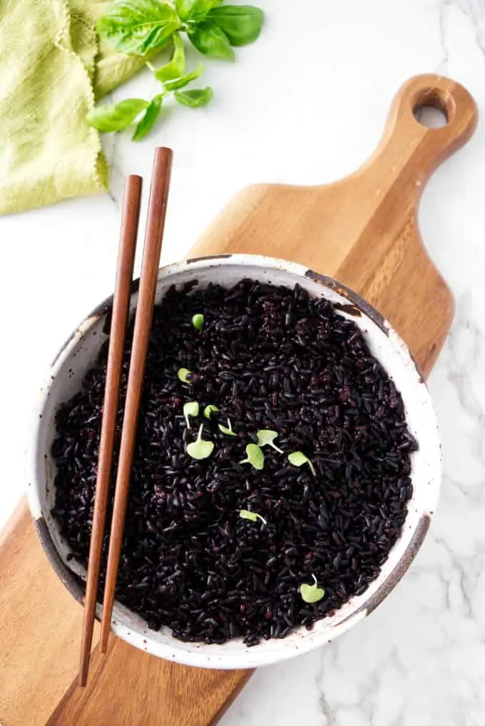 Black rice in a bowl with chopsticks on the side.