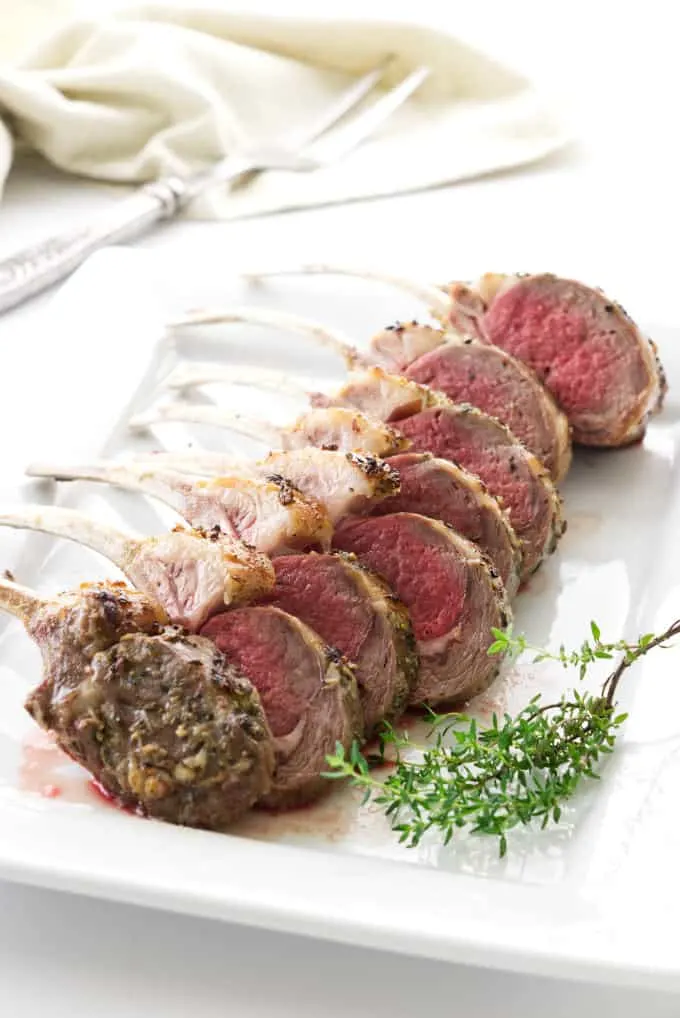 Roasted rack of lamb sliced into individual servings and placed on a serving plate.