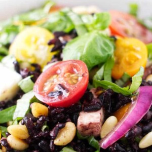 Close up of a tomato in a bowl of black rice salad.