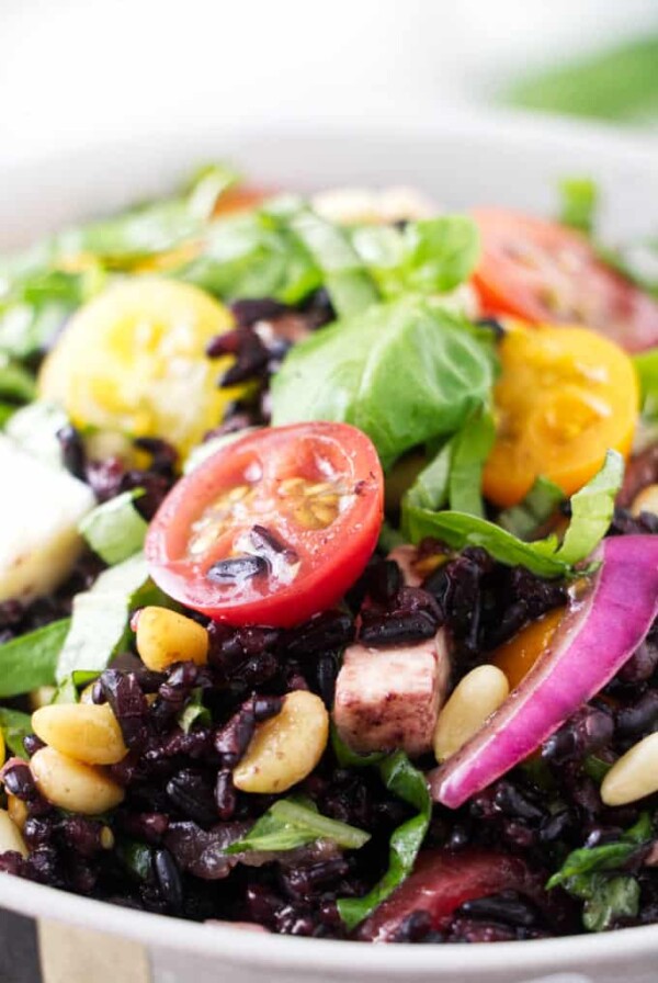 Close up of a tomato in a bowl of black rice salad.