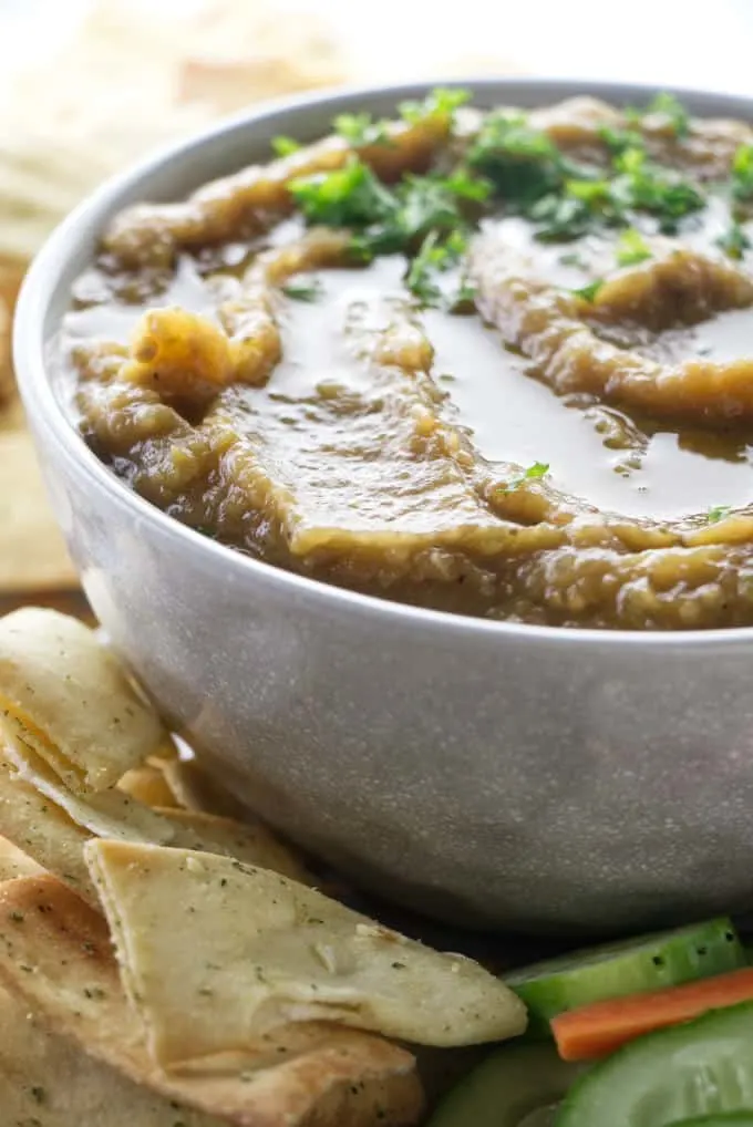 A bowl of eggplant caviar with crackers on the side.