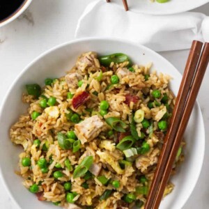 Two bowls of pork fried rice with chopsticks.