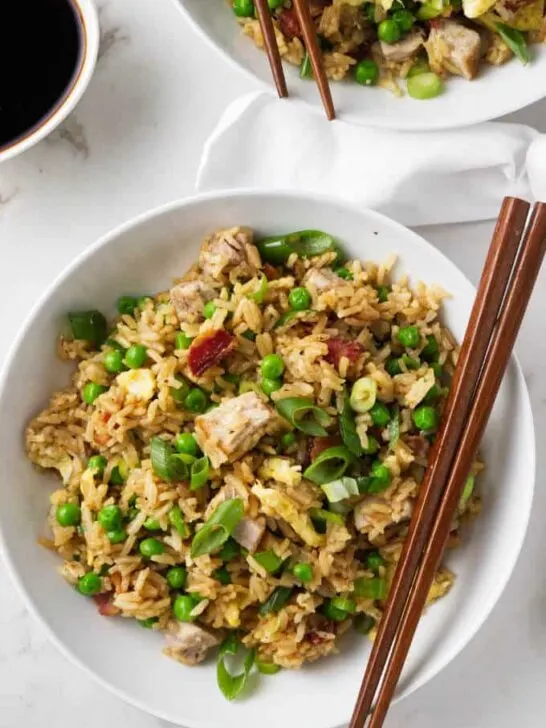 Two bowls of pork fried rice with chopsticks.