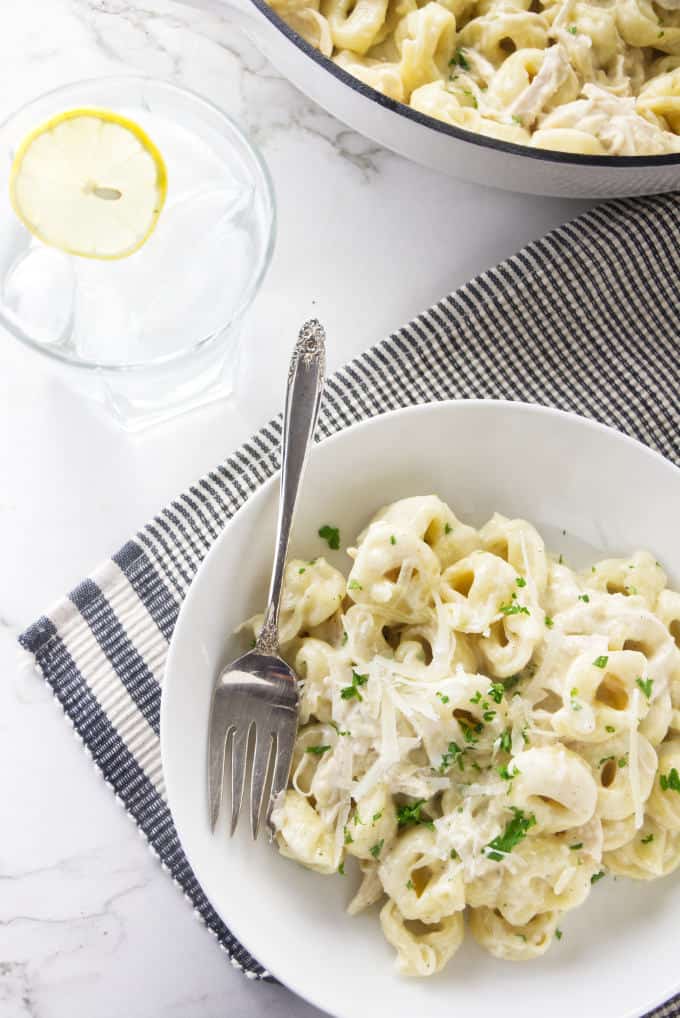 A plate of Chicken Tortellini Alfredo and a glass of ice water.