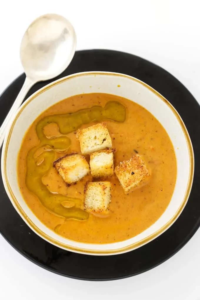 Overhead photo of Fire-Roasted Tomato Bisque with croutons and olive oil on top.