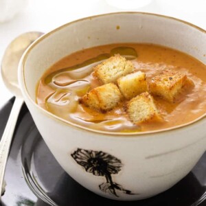 A bowl of Fire-Roasted Tomato Bisque with croutons on top.