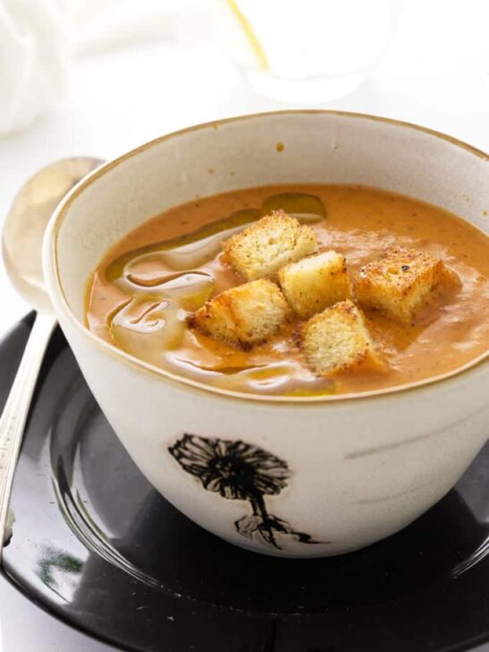 A bowl of Fire-Roasted Tomato Bisque with croutons on top.