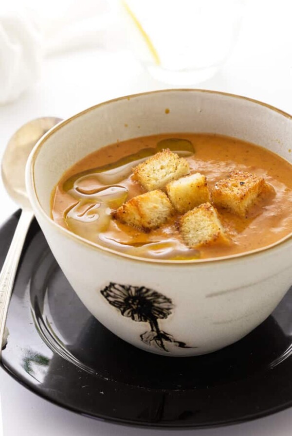 A bowl of Fire-Roasted Tomato Bisque with croutons on top.