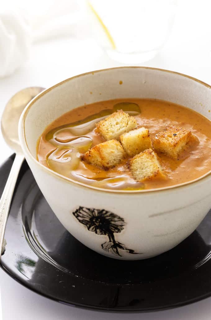A bowl of Fire-Roasted Tomato Bisque with croutons on top.