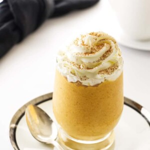 a glass filled with pumpkin mousse and whipped cream on top.