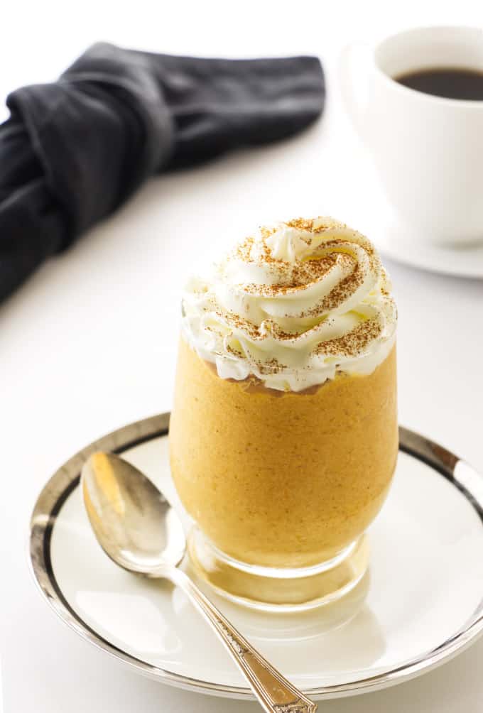a glass filled with pumpkin mousse and whipped cream on top.