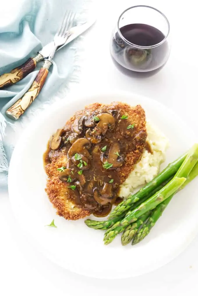 Jaeger Schnitzel and mushroom sauce on a plate with asparagus.