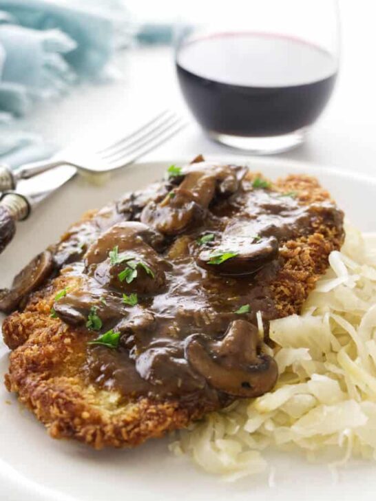 Jaeger Schnitzel and mushroom sauce on a plate with red wine in the background