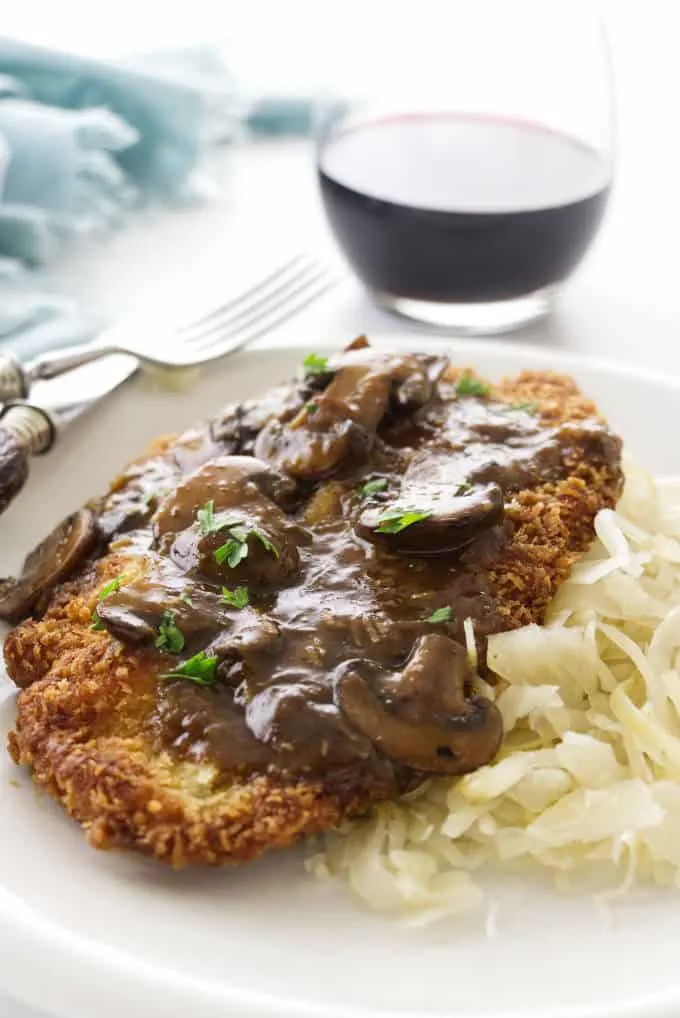 Jaeger Schnitzel and mushroom sauce on a plate with red wine in the background