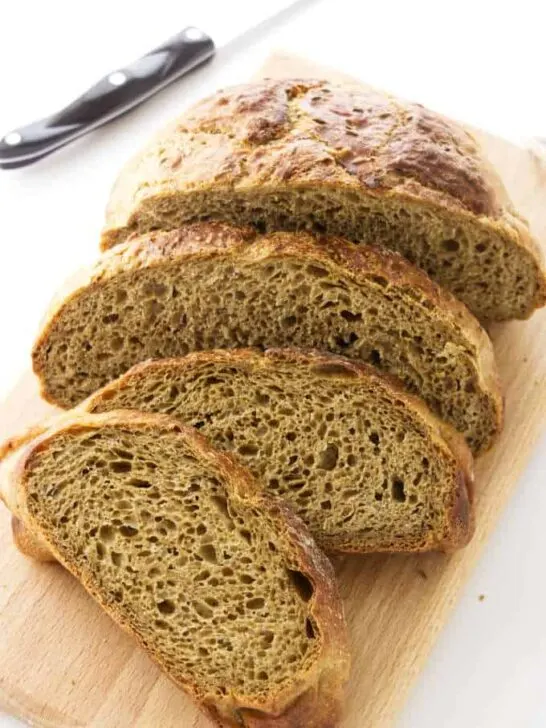 No-knead rye bread slice on a cutting board.