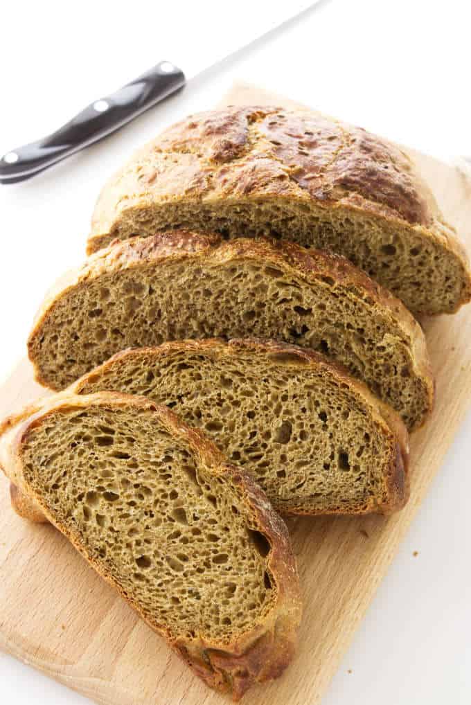 No-knead rye bread slice on a cutting board.