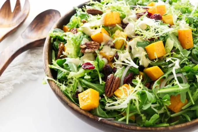 A large serving bowl of roasted butternut squash green salad