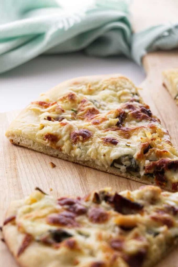 Two slices of chicken spinach pizza with a napkin in the background.