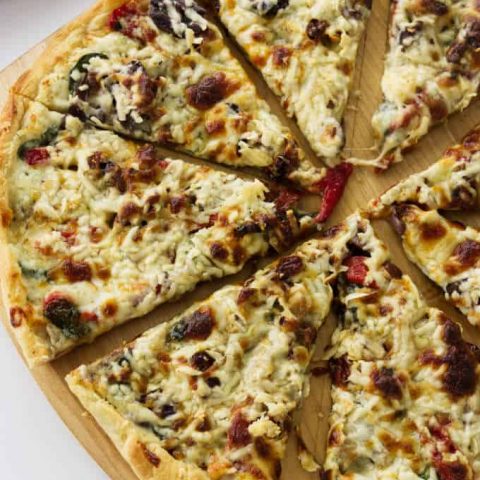 A freshly baked mushroom pizza sliced on a pizza peel.