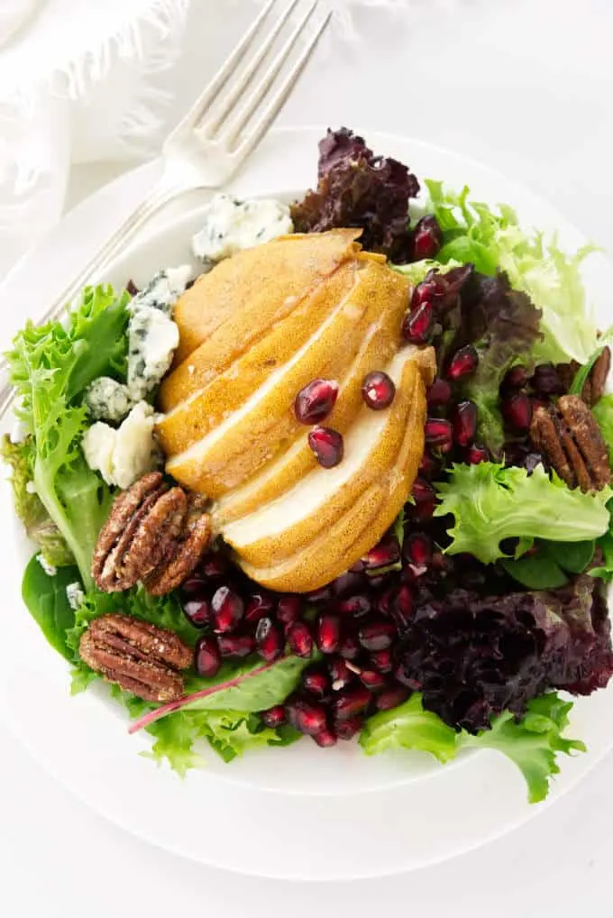 A serving of pomegranate and pear salad with blue cheese and candied pecans.