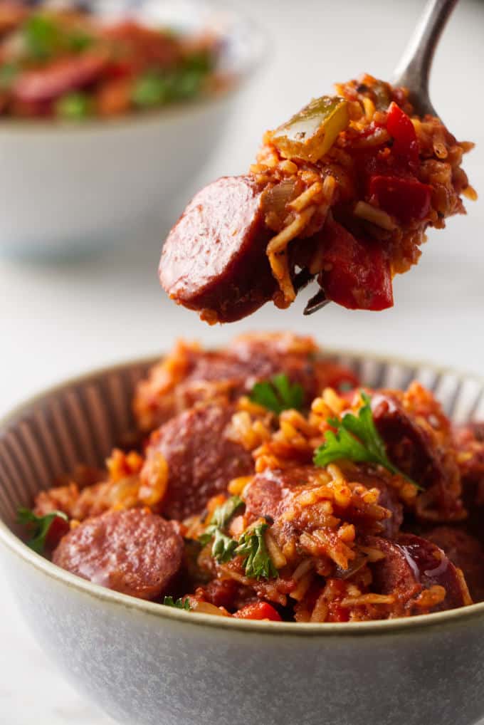 A fork scooping out a bite of sausage and rice.