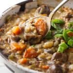 A bowl of wild rice and mushroom soup with a spoon.