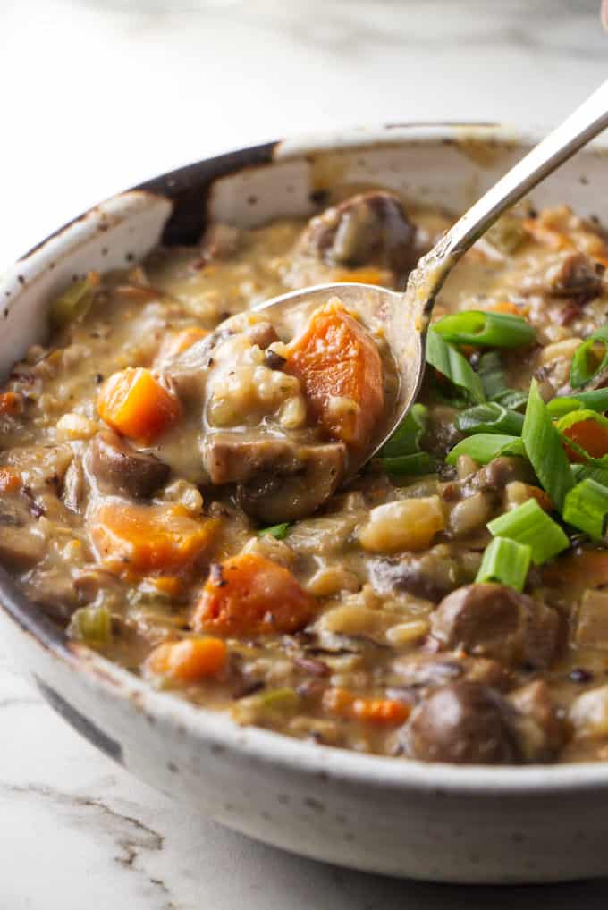 A bowl of wild rice and mushroom soup with a spoon.