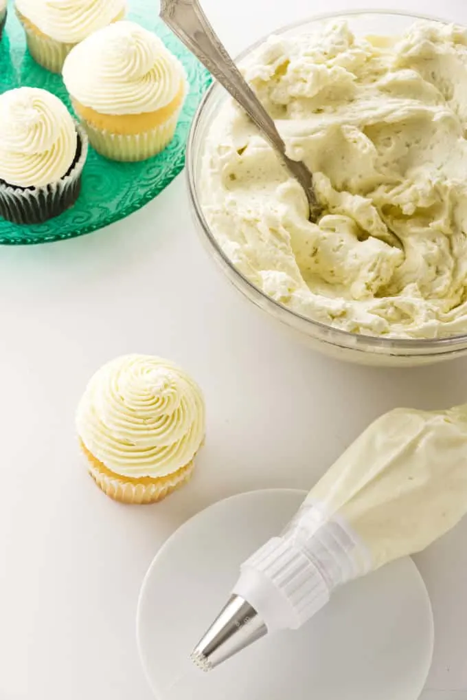 Cooked flour ermine frosting in a bowl next to some cupcakes and a piping bag.