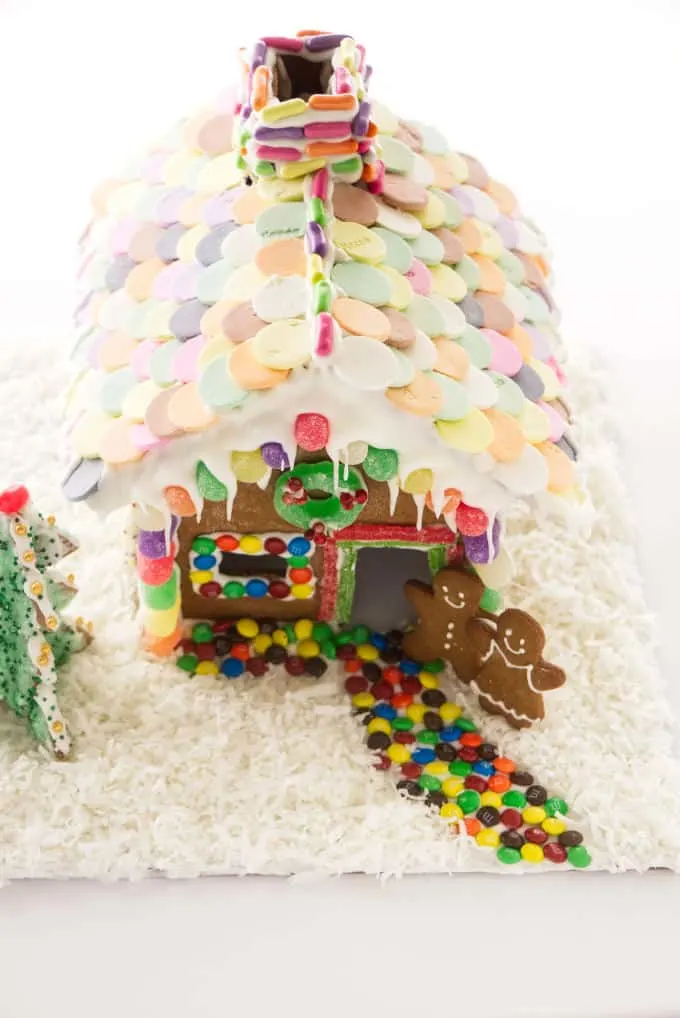 A decorated gingerbread house with a necco wafer roof and coconut flakes for snow.
