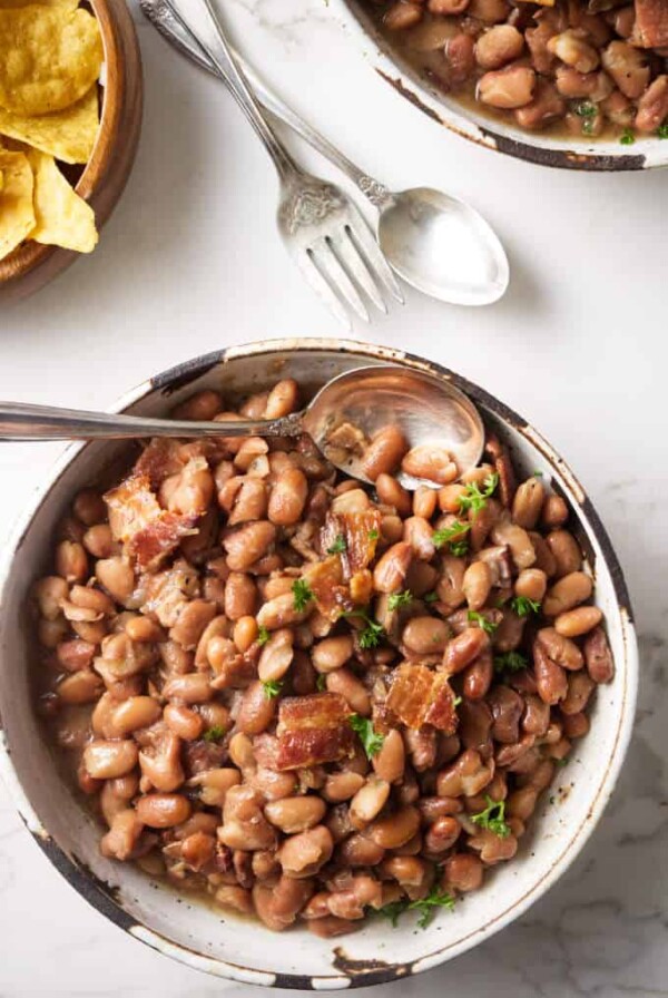 Two bowls of instant pot pinto beans with some corn chips.