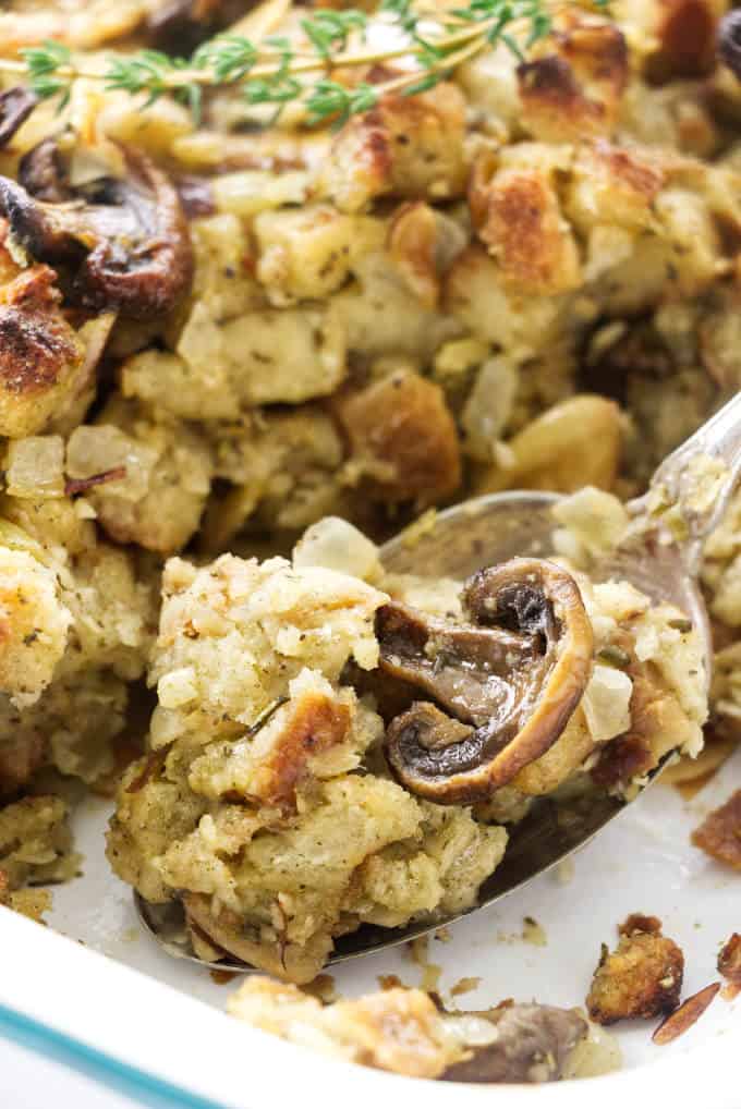 A spoon scooping out some mushroom stuffing from a casserole dish.