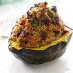 A sausage stuffed acorn squash with the stuffing piled high on the squash.