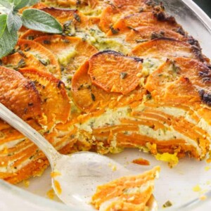 Scalloped sweet potato casserole in a casserole dish showing the layers of potato and cheese.