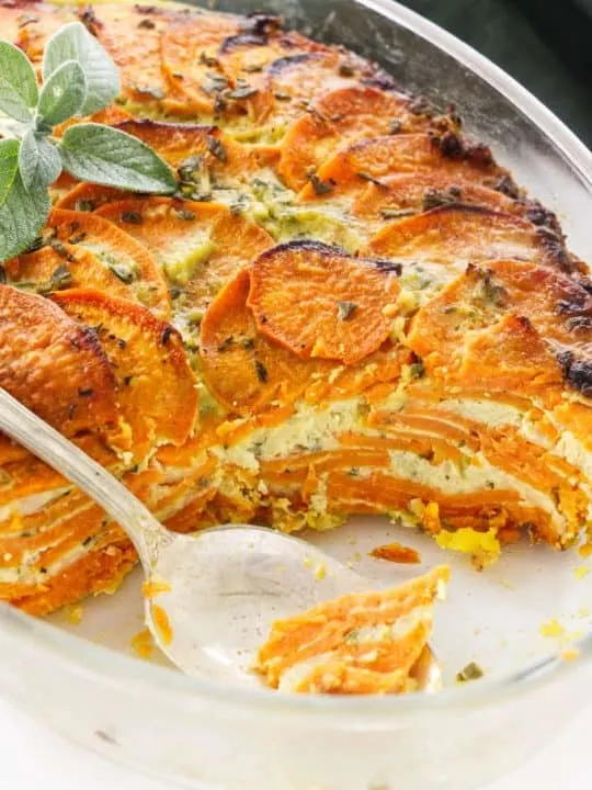 Scalloped sweet potato casserole in a casserole dish showing the layers of potato and cheese.