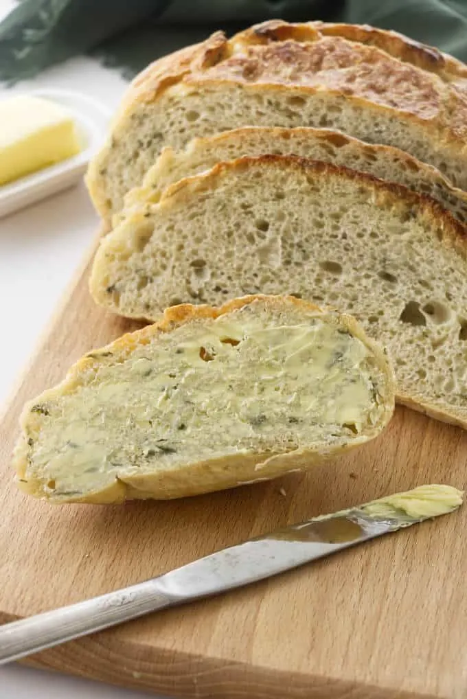 No-knead rosemary bread sliced and slathered in butter.