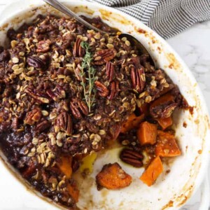 Sweet potato casserole in a white dish with pecan streusel on top.
