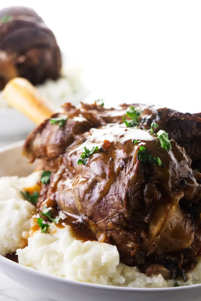 Instant Pot lamb shank on a bed of mashed potatoes.