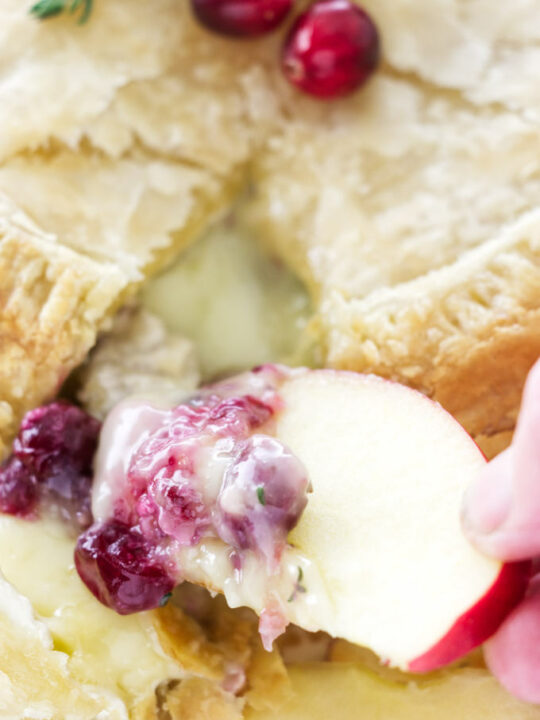 Close up ov apple slice with cranberry sauce and brie
