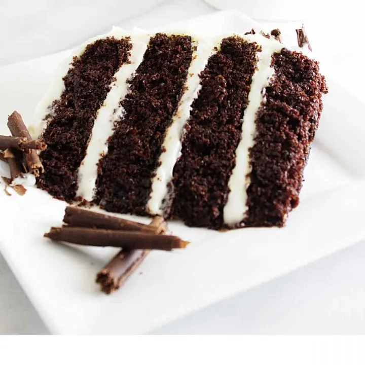 A slice of chocolate cake with cream cheese frosting on a dessert plate.