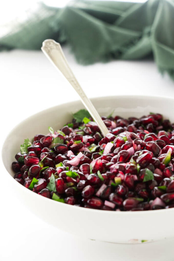 Dish of Pomegranate Salsa with a serving spoon, green napkin in background