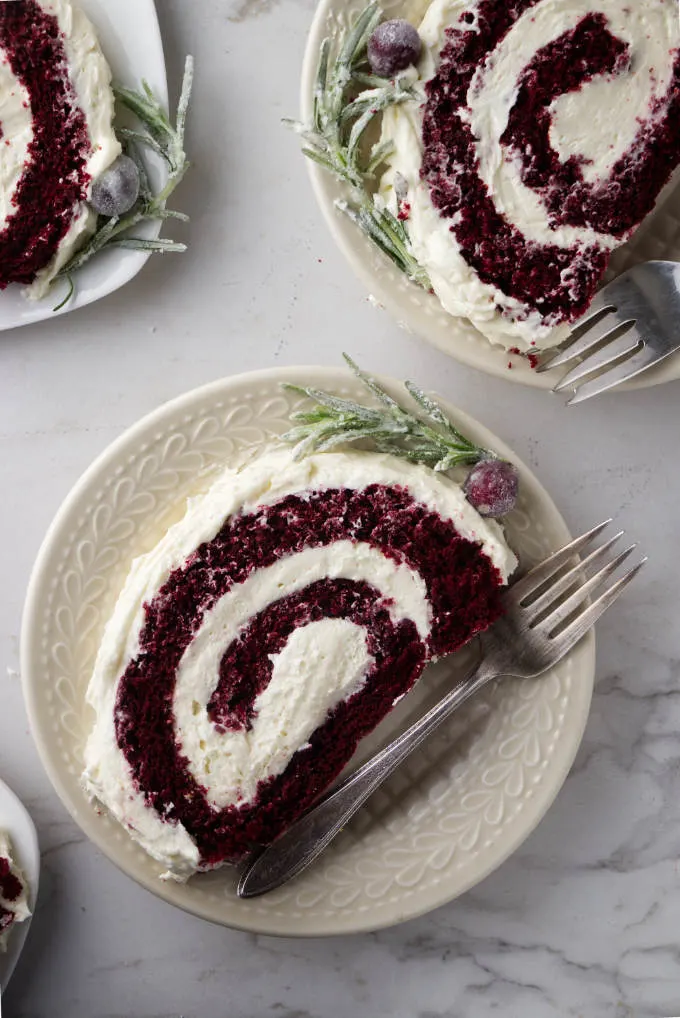 Slices of red velvet cake roll on dessert plates.