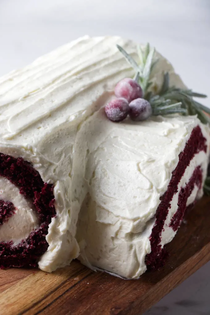 Close up of a red velvet cake roll covered in ermine frosting.
