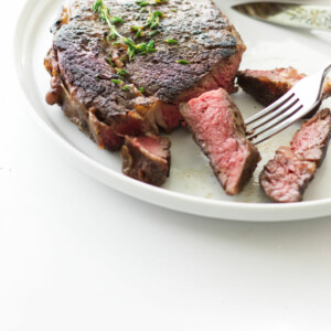 A ribeye steak sliced on a plate after being cooked in the oven.