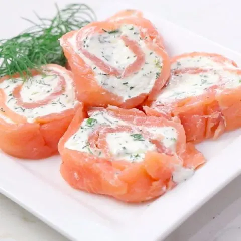 Smoked salmon pinwheels on a plate with fresh dill.