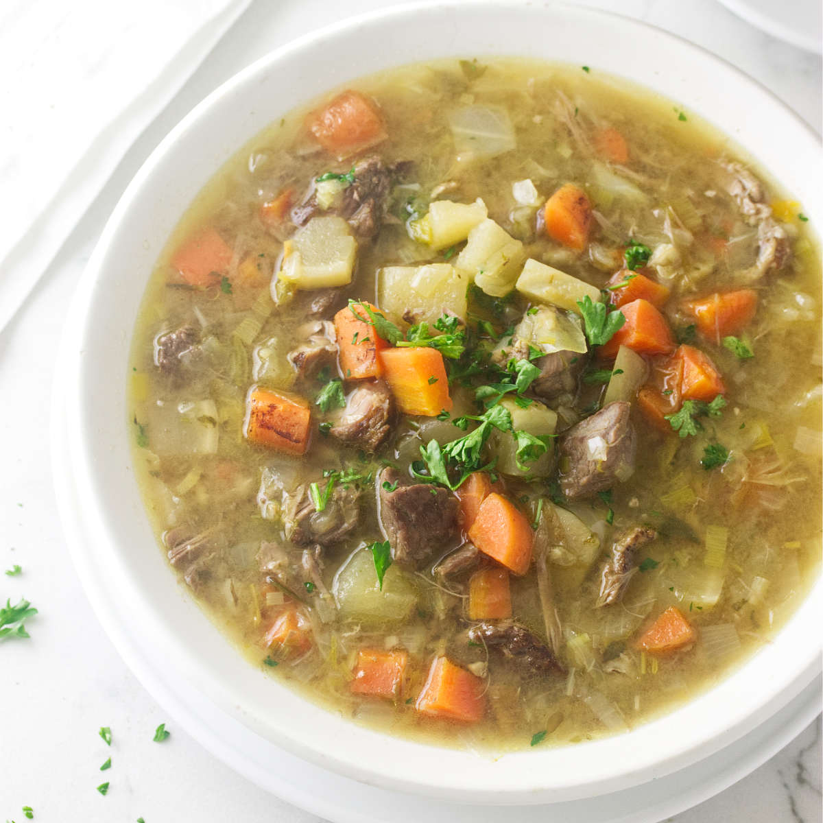 A bowl of Scotch broth showing chunks of lamb and vegetables.