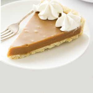 A slice of butterscotch tart on a white dessert plate.